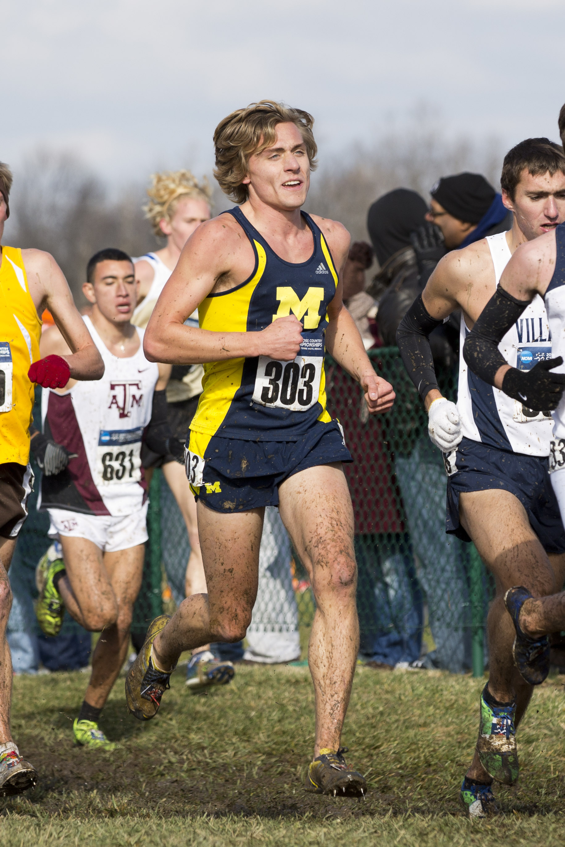 A young man in University of Michigan gear runs a race against other competitors.