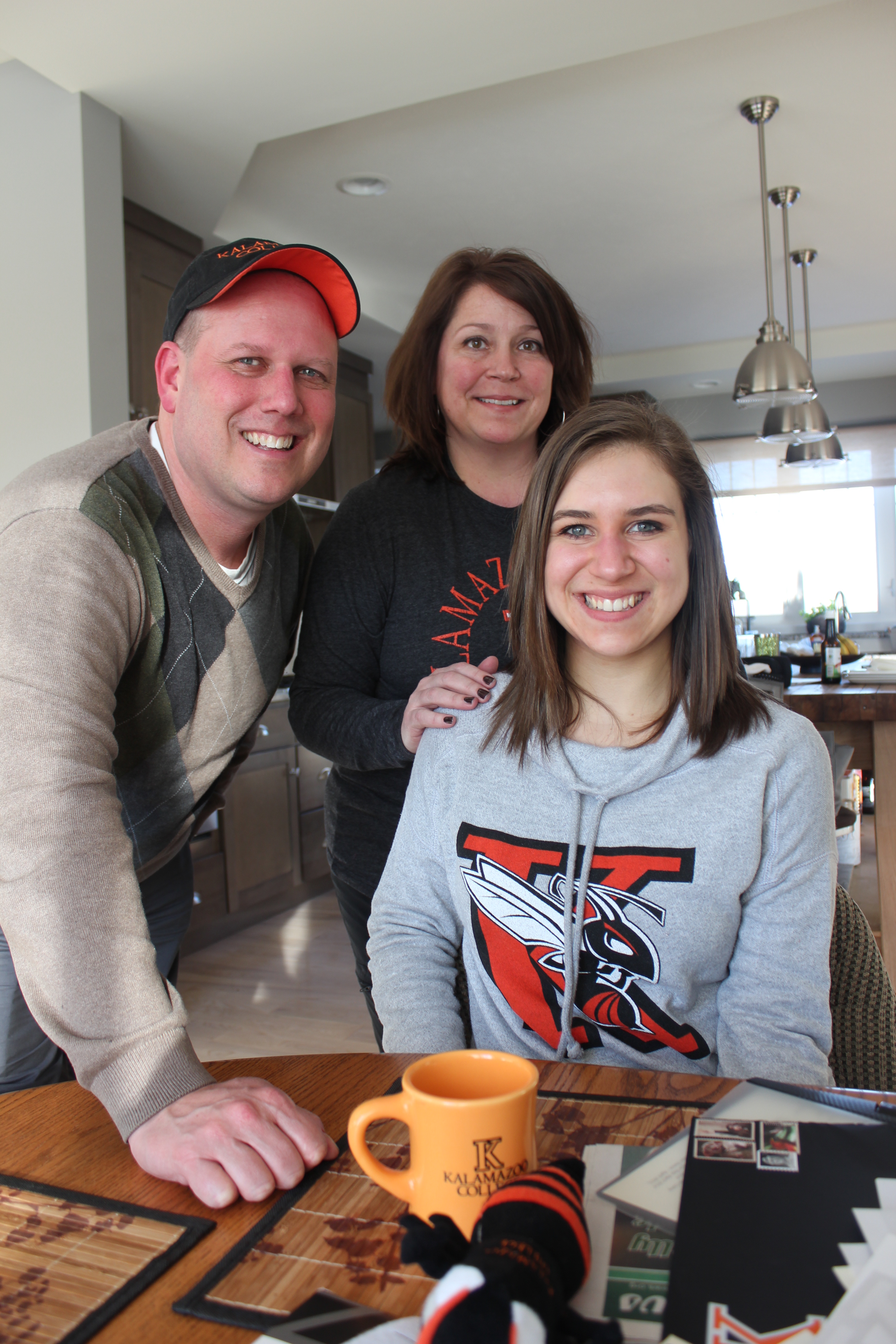 Two parents smile with their teen daughter.