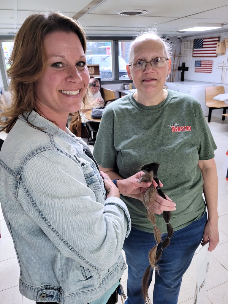 A woman hands hair donations to another woman who is having cancer treatments.
