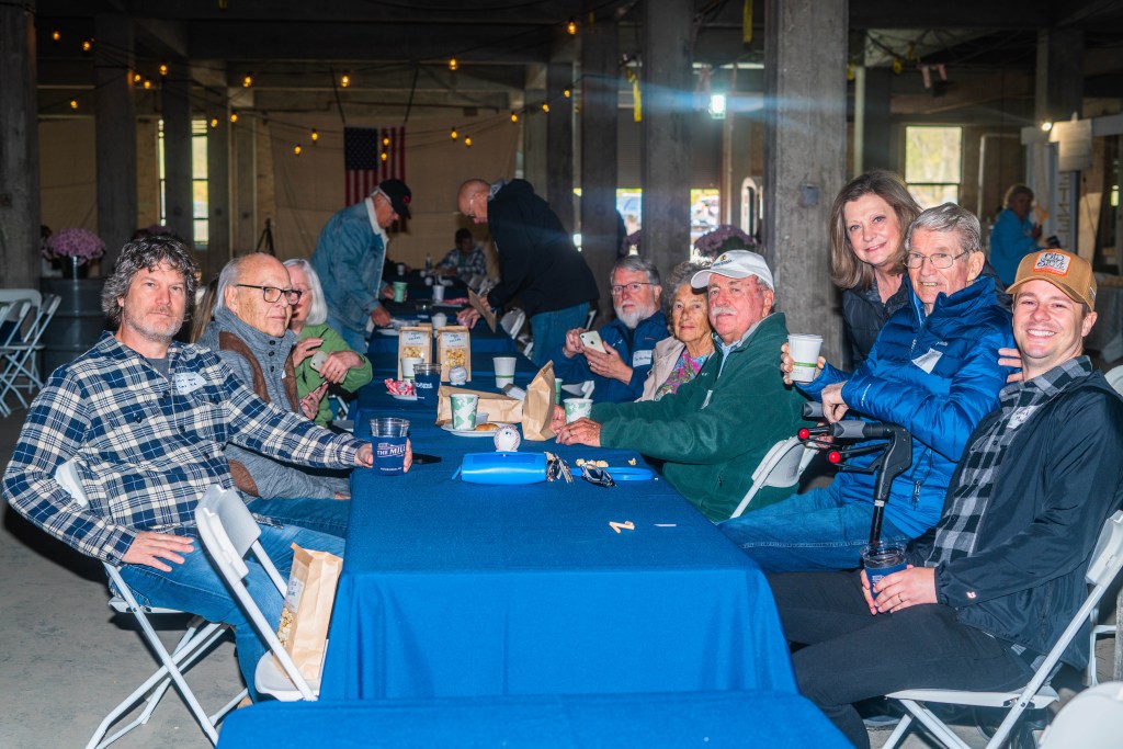 Several people in flannel and coats sit around a table.