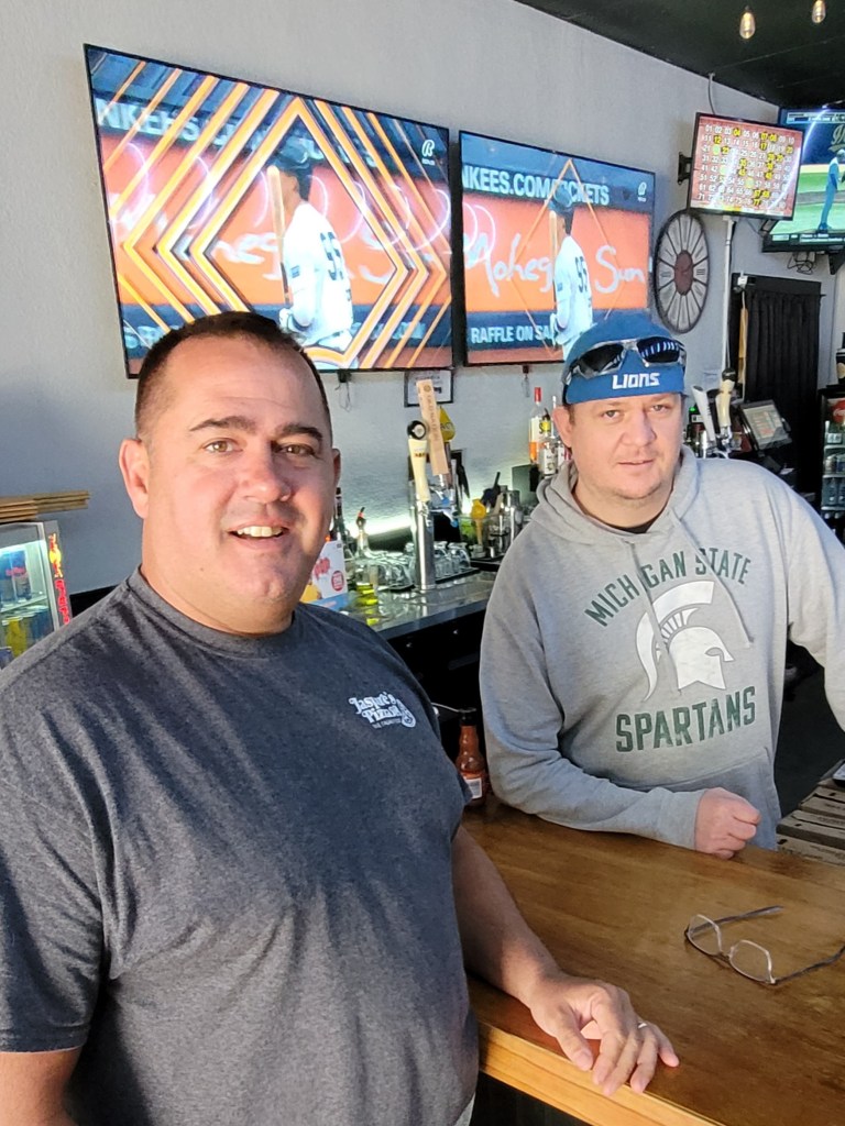Two men stand by the bar at the pizza restaurant.