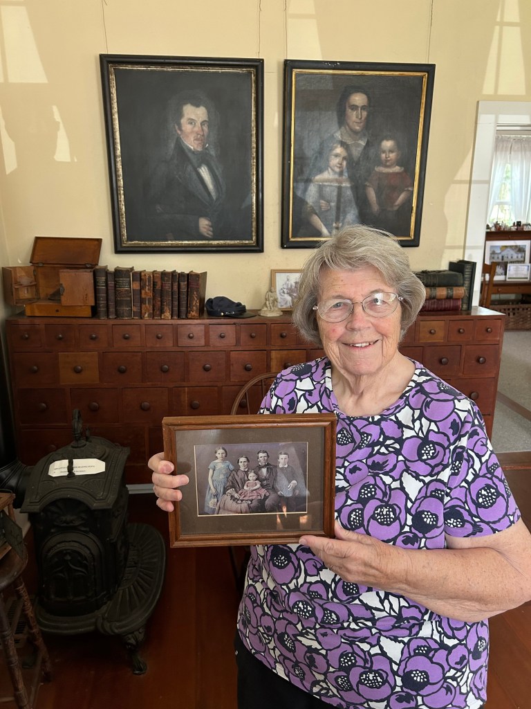 A woman holds up old portrait photos.