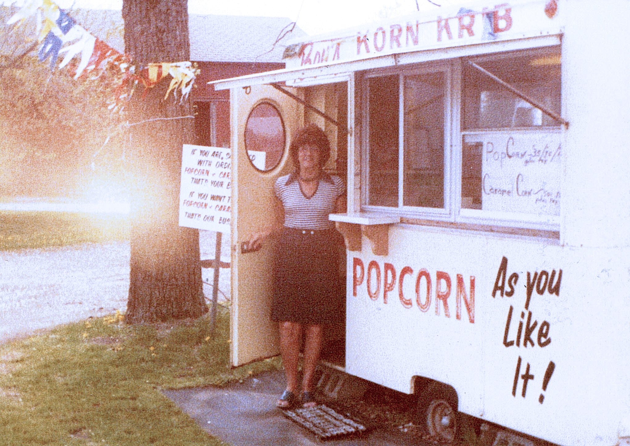 Brakefield, Bev’s Korn Krib picture (1) A vintage photo of a woman stepping out of a food truck that sells popcorn.
