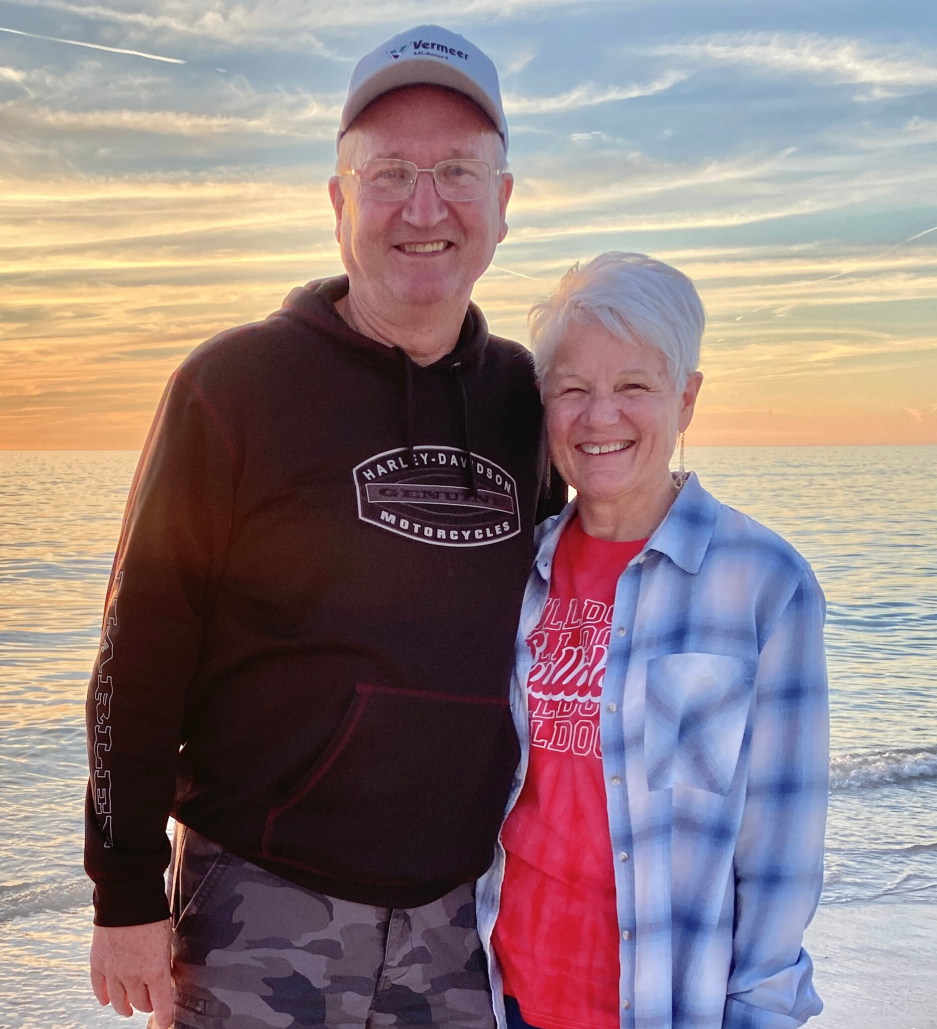 Wedding Anniversary, Lash An older couple stands in front of a sunset.