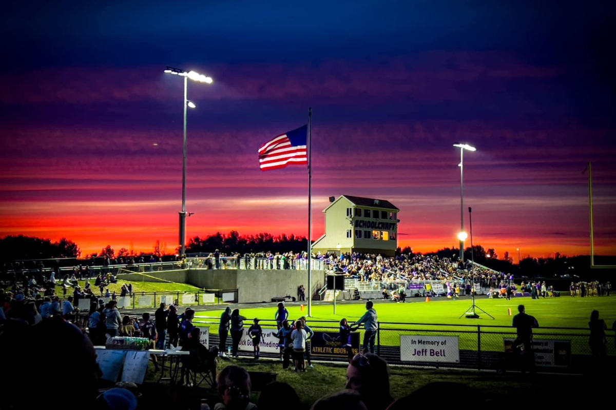An athletic field at sunset with an American flag flying at center.