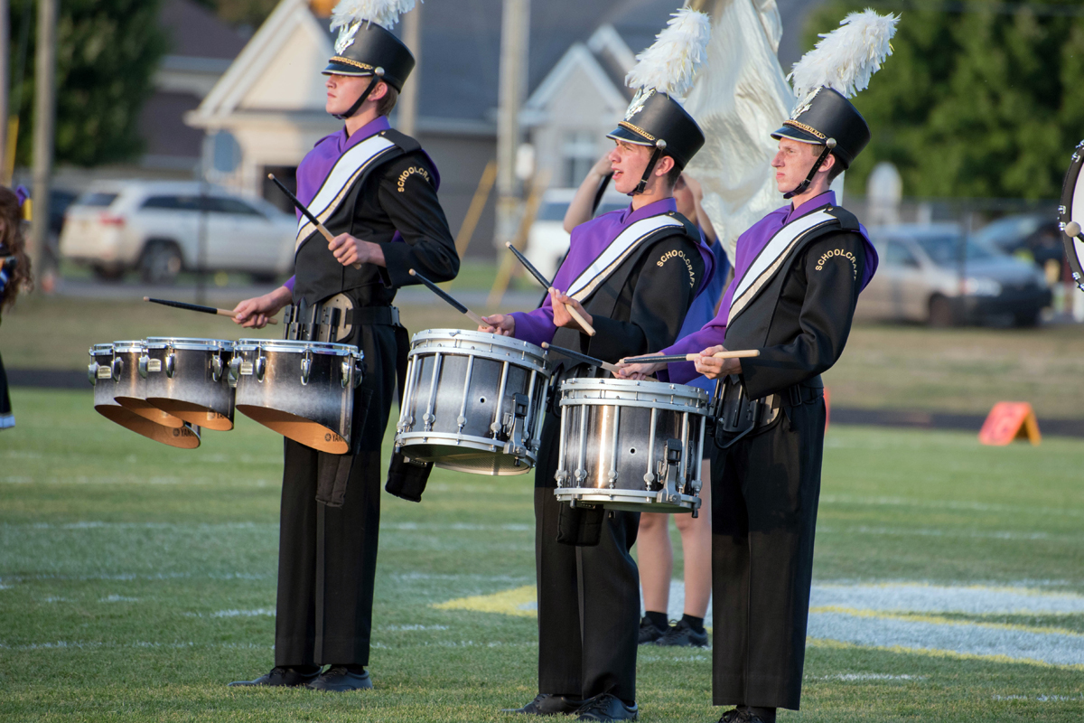 schoolcraftband Three kids in purple band uniforms play the drums.