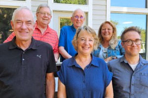 A group of six people stand near each other.