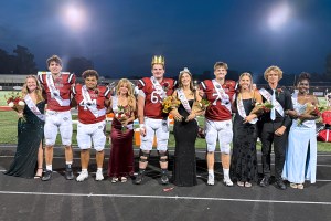 Students stand in formal attire and football uniforms as part of the homecoming court lineup.