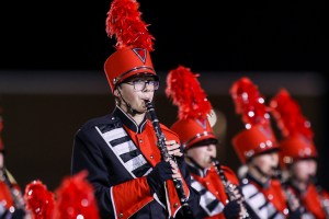 A red uniformed marching band member plays the clarinet.