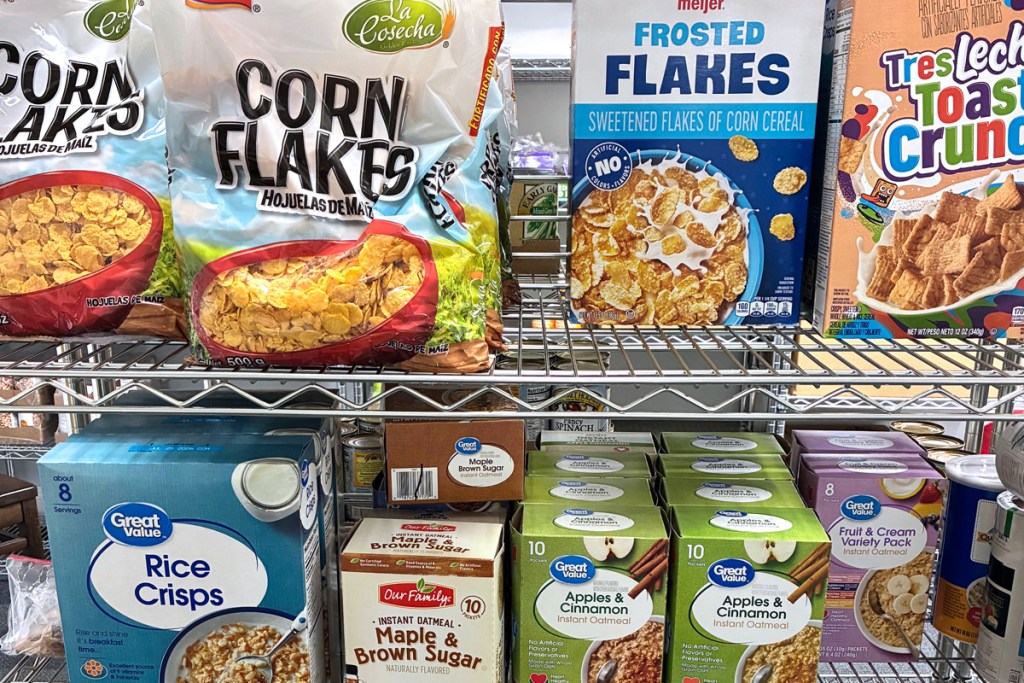 Several kinds of nonperishable food items on a metal shelf.