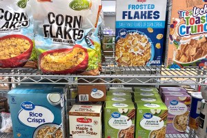 Several kinds of nonperishable food items on a metal shelf.