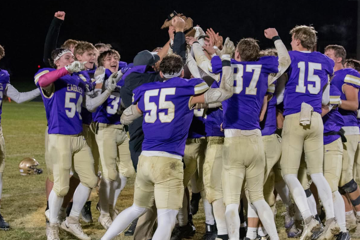 Purple uniformed football players celebrate a win.