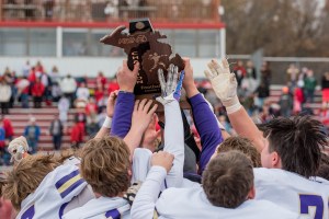Football players hoist a trophy high above their heads.