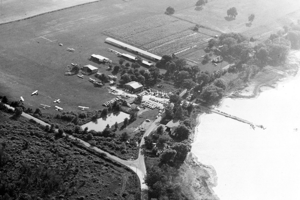 An aerial view of an airfield positioned alongside a large lake.