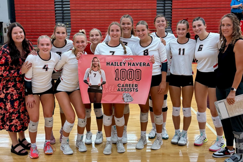 A volleyball team holds a banner honoring Hailey Havera, one of the players.