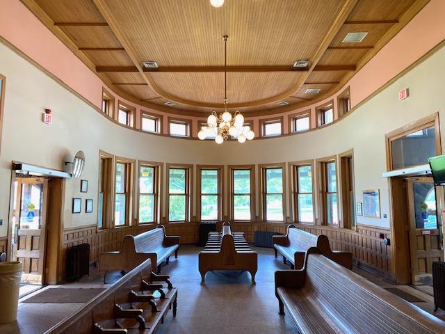 An old train station interior with wooden benches and rounded details.