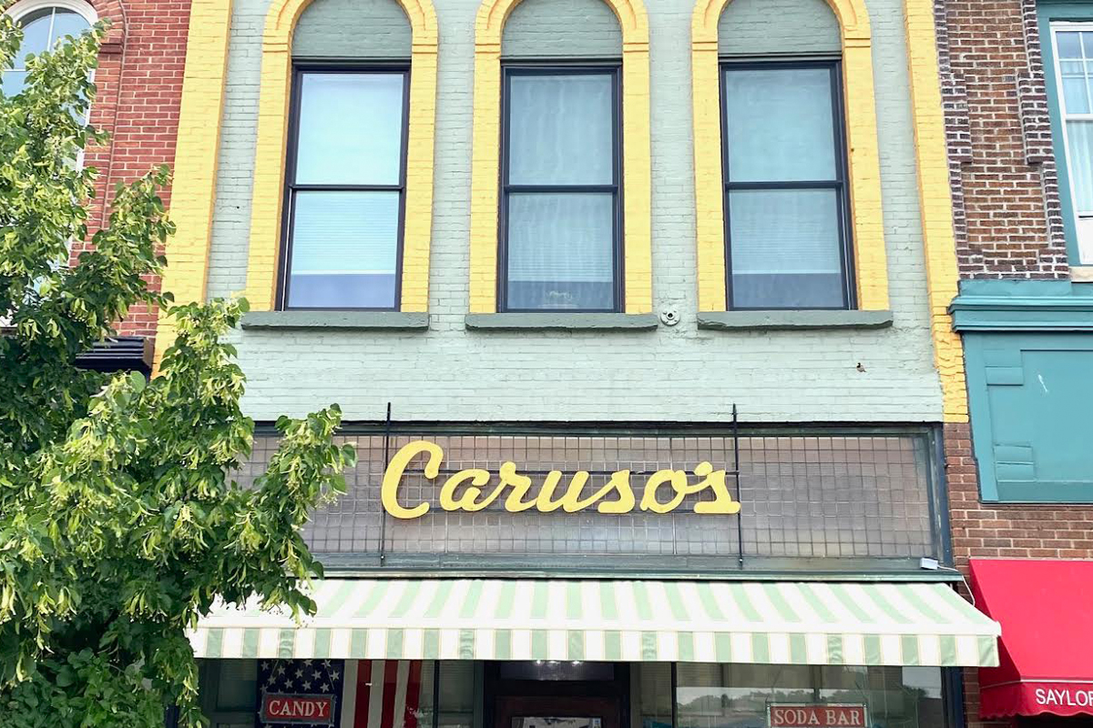 ontheroad_carusos An old storefront with yellow trim and a sign reading "Caruso's."
