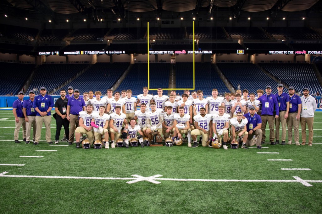 Several rows of football players posing on Ford Field.