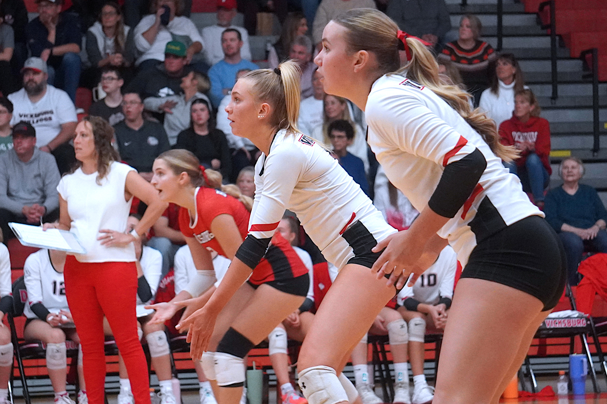 Three volleyball players watch intently.