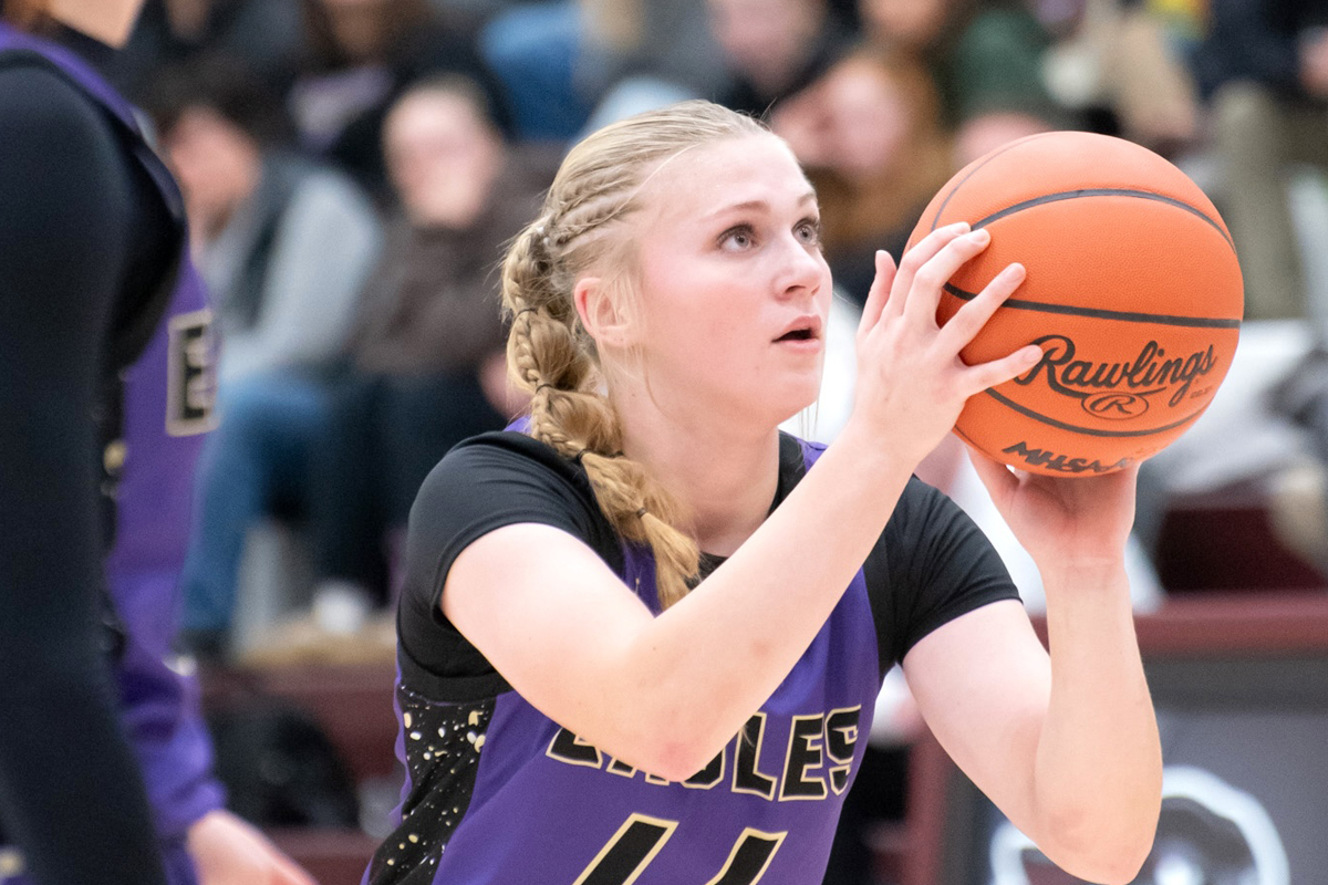 A basketball player in purple gets ready to shoot the ball.