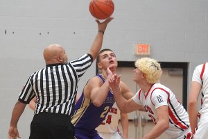 The ref holds the ball high while two basketball players anticipate the drop.
