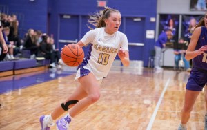 A basketball player dribbles the ball down the court.