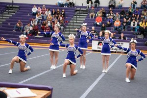 Six purple-uniformed cheerleaders in the middle of a competitive performance.