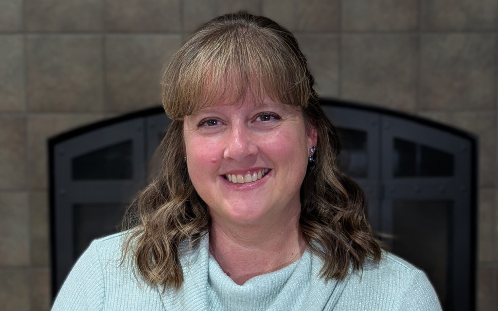 A woman smiling with a blue sweater on.