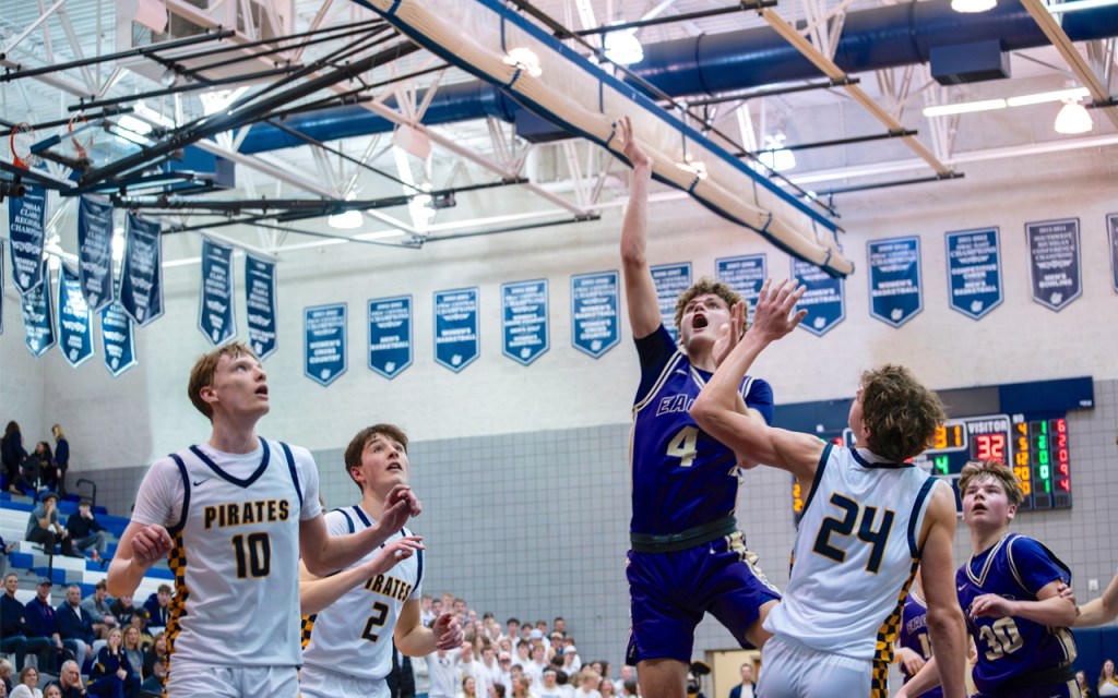 Basketball players leap into the air desperate to make a basket.