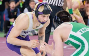 Two wrestlers in uniform size each other up before making a move.