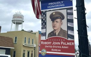 A patriotic banner hanging from a streetlight honors a veteran named Robert John Palmer.
