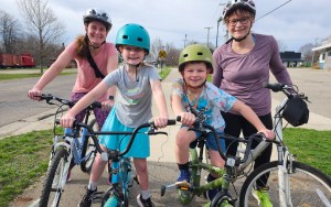 Two adult women and two children ride bikes together.