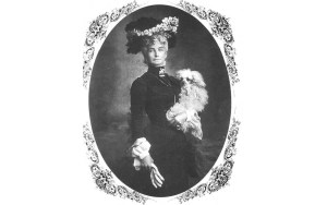 A Victorian woman poses with a poodle in her arm.