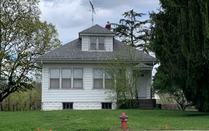 A small white house near a fire hydrant.