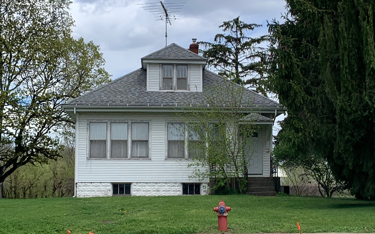 A small white house near a fire hydrant.