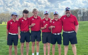 A group of red-shirted young golfers on the green.