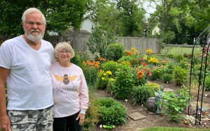 A couple standing in front of a colorful garden.