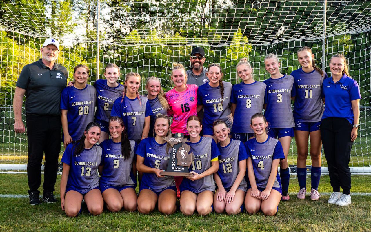 schoolcraftsoccer A female soccer team poses in purple shirts with a Michigan-shaped trophy.