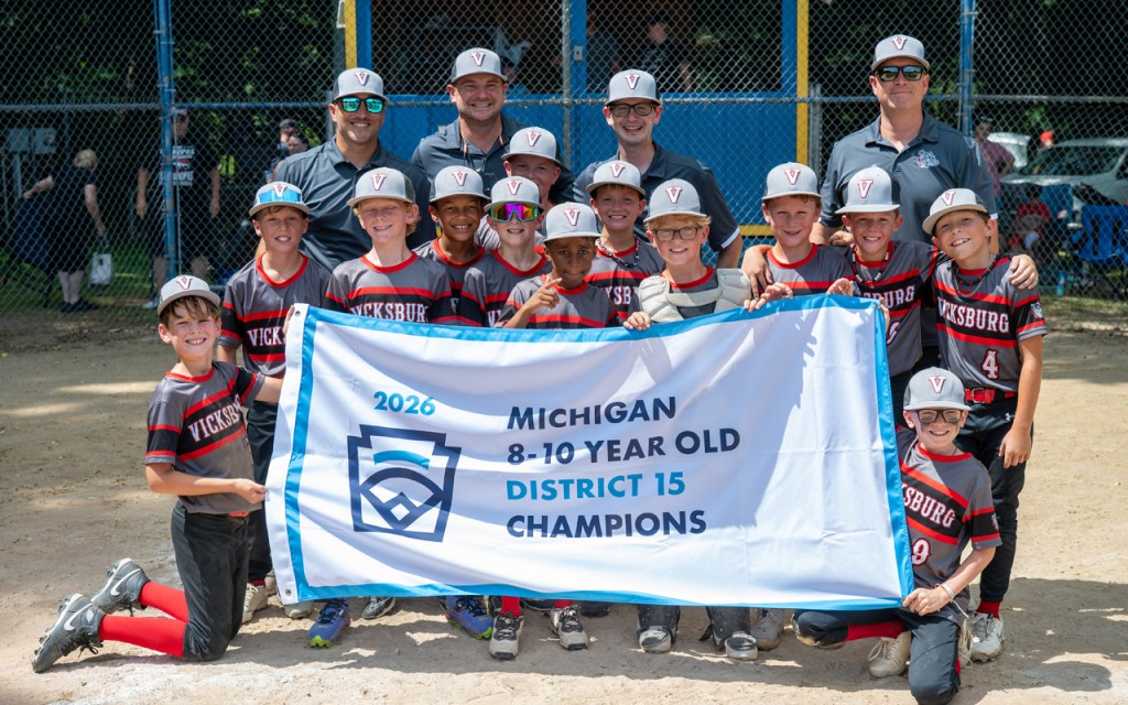 Several kids in baseball uniforms hold up a victory banner.