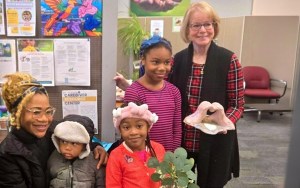 A family with a mom and three kids holds art projects with a South County Community Services representative.