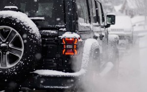 A black jeep drives through heavy snow.