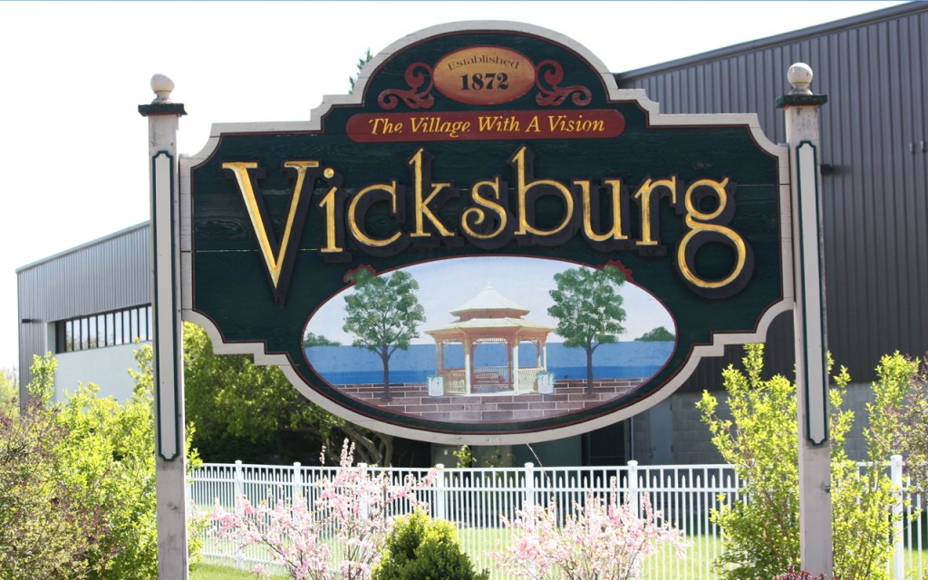 A colorful sign reads "The Village with a Vision - Vicksburg."