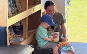 An adult and a young child look through books on the mobile library that is the Big Read Machine.
