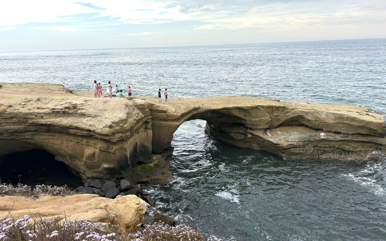 ontheroadagain_sandiego A group stands atop some rock cliffs set into the ocean.