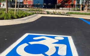 A parking lot behind some colorful buildings has a freshly painted handicapped indicator painted on a space.