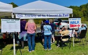 Several people stand under a tent that reads St. Vincent de Paul.